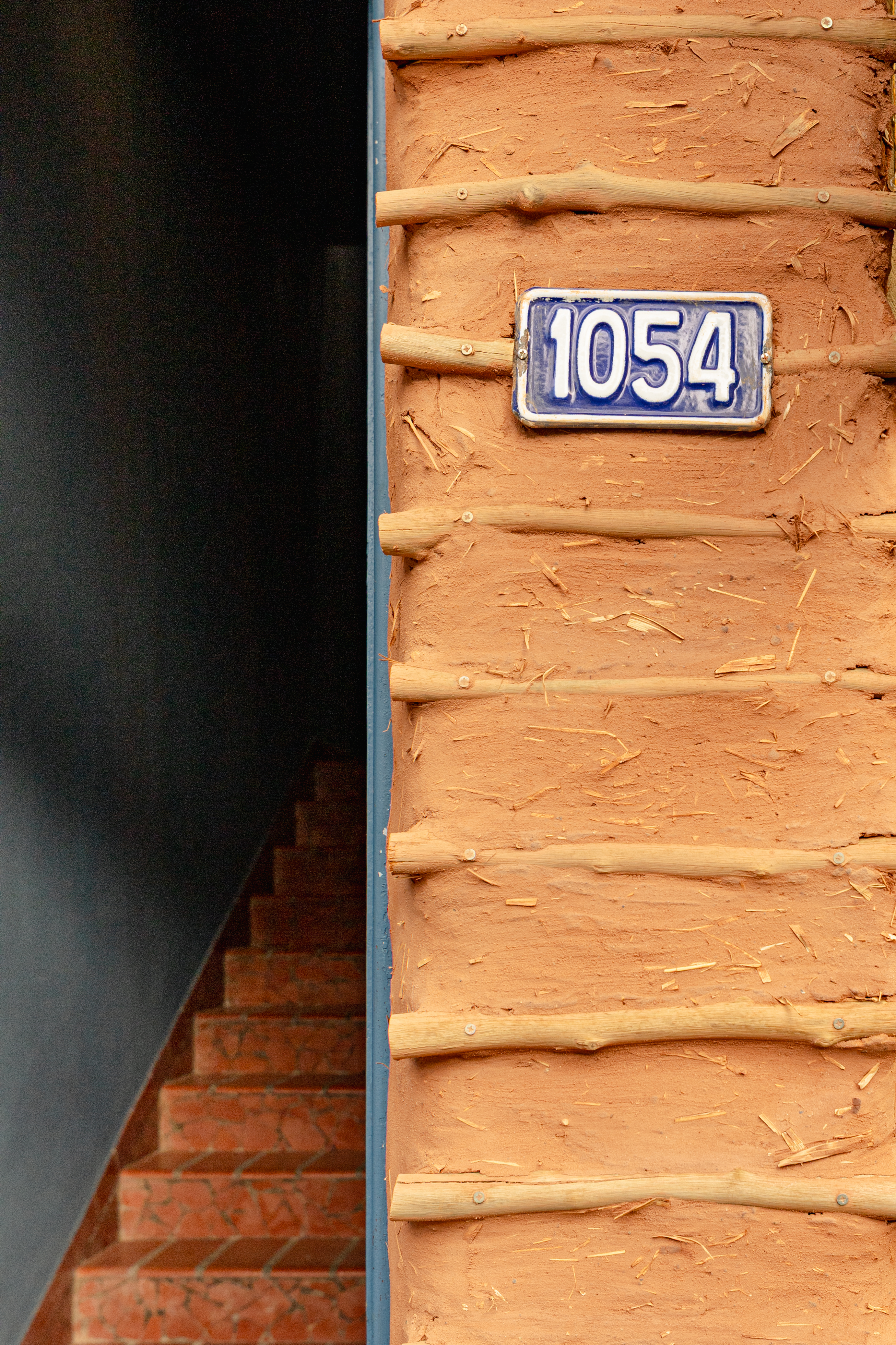 Entrada do escritório Arq Besô — porta azul e tijolos